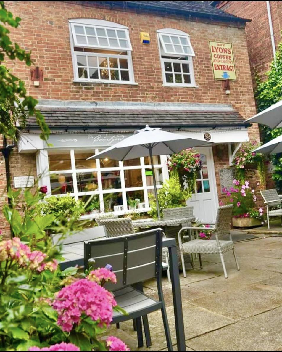 The Courtyard Cafe entrance with pink flowers and parasols